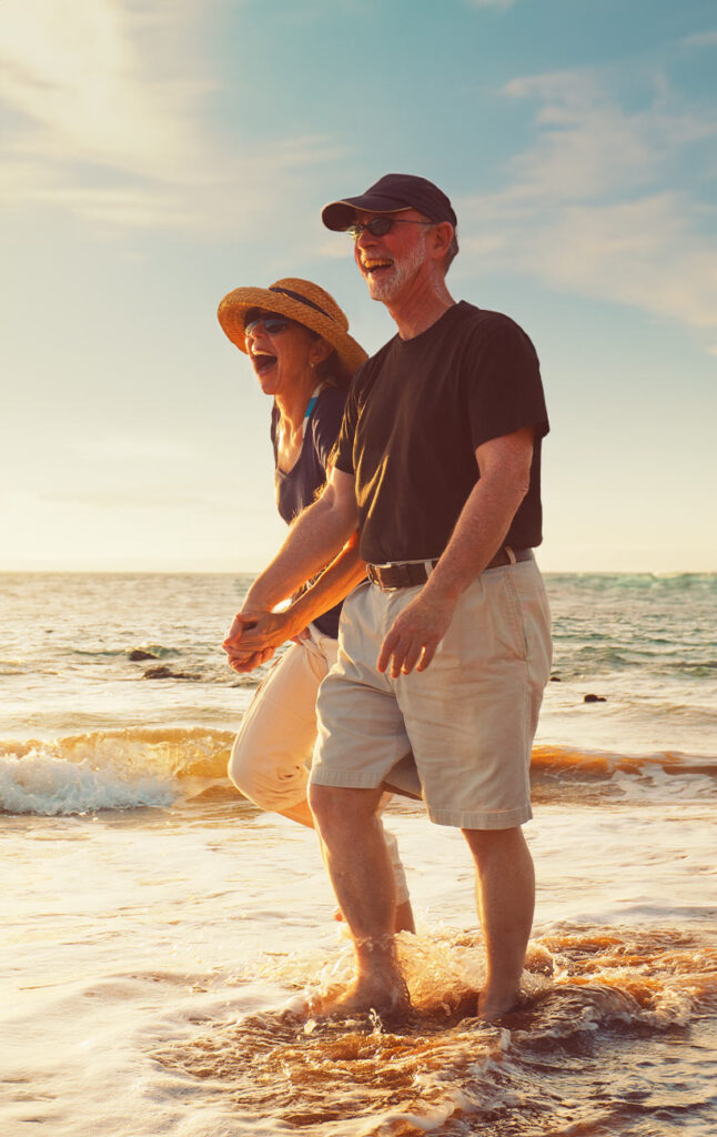 senior couple walking on the beach shore line retirement future